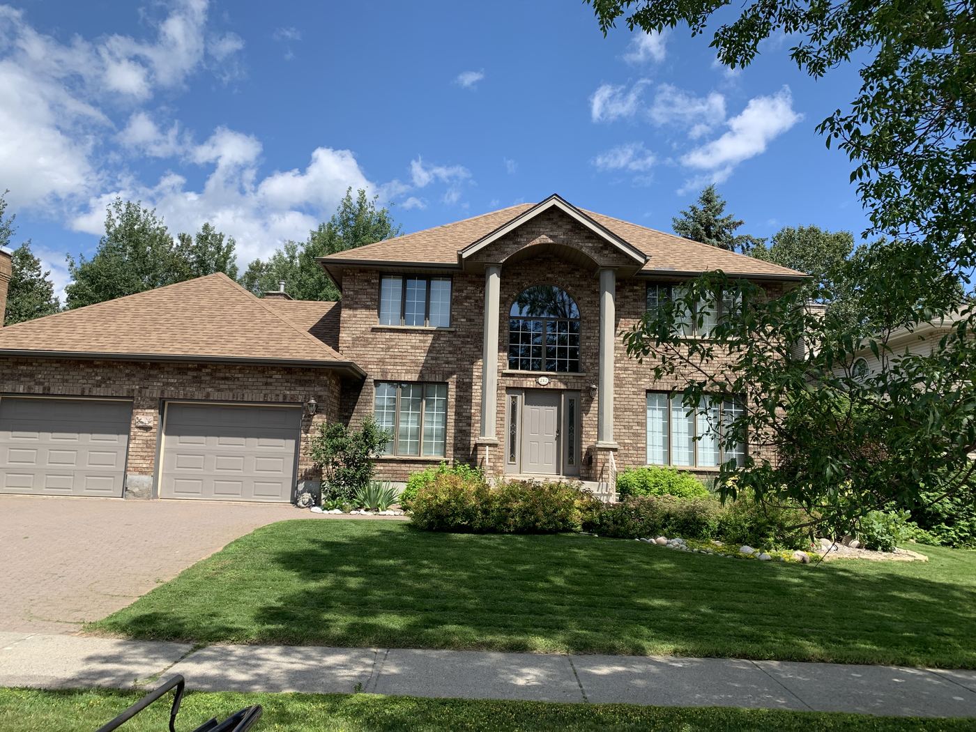 A lush, fully established lawn in front of a large Thunder Bay home