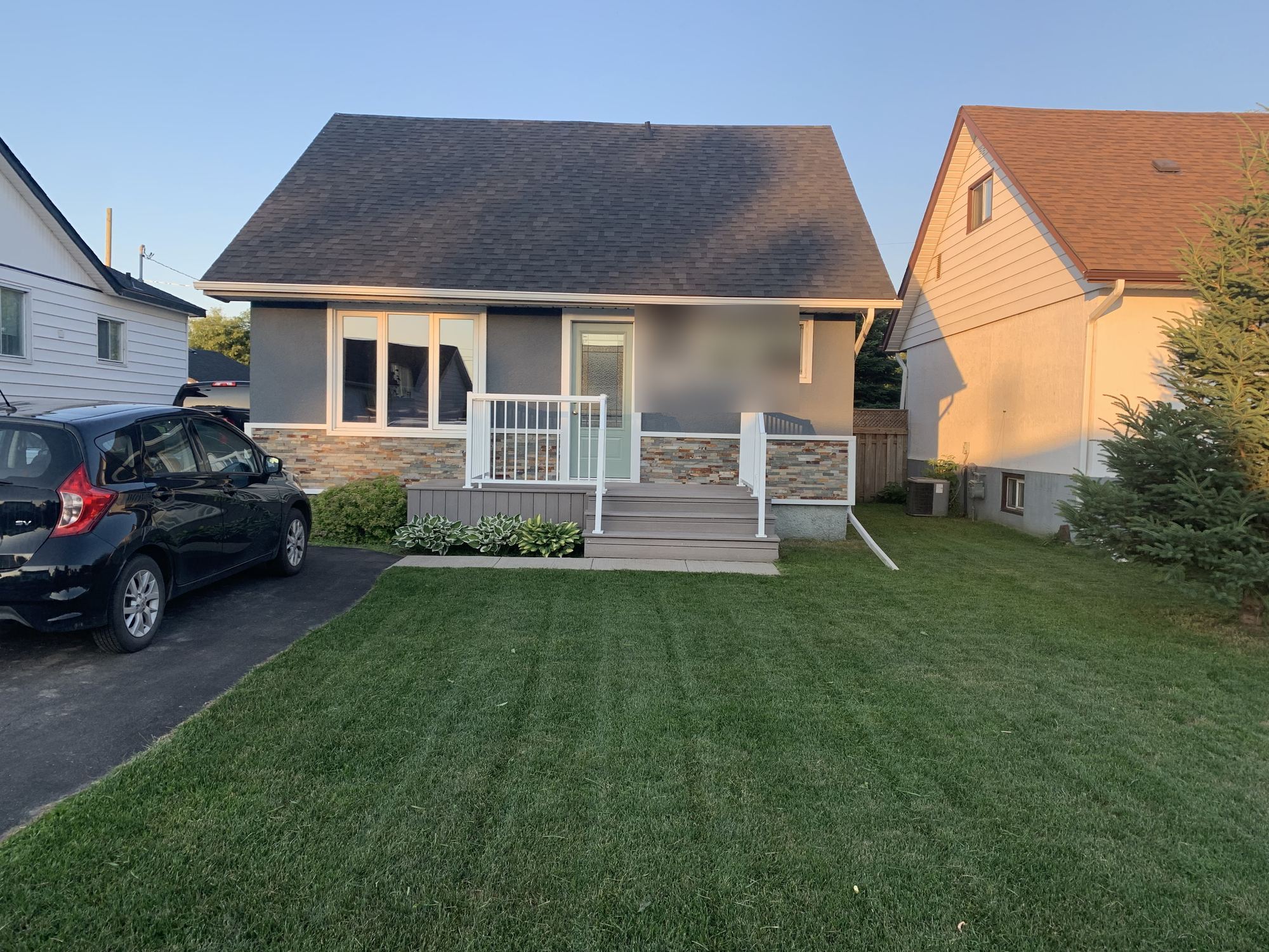 A freshly mowed front lawn with crisp striping in front of a home in Thunder Bay, golden-hour light